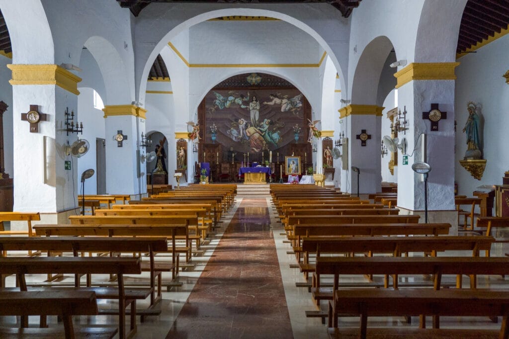 Intérieur d'église, bancs vides, autel, fresque murale.