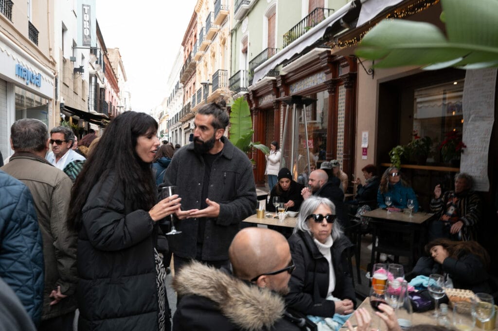 People conversing on busy street cafe patio