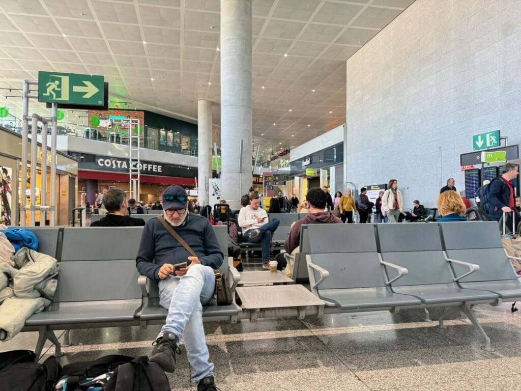 Passengers waiting in airport terminal seating area.