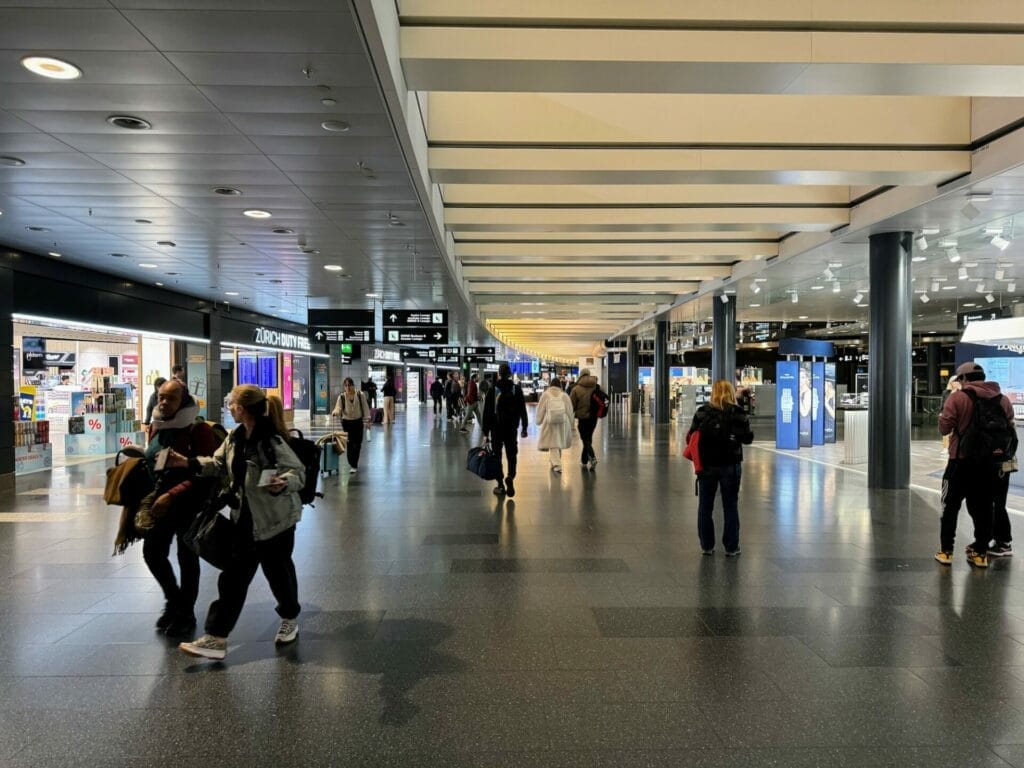 Busy airport terminal with passengers and shops.