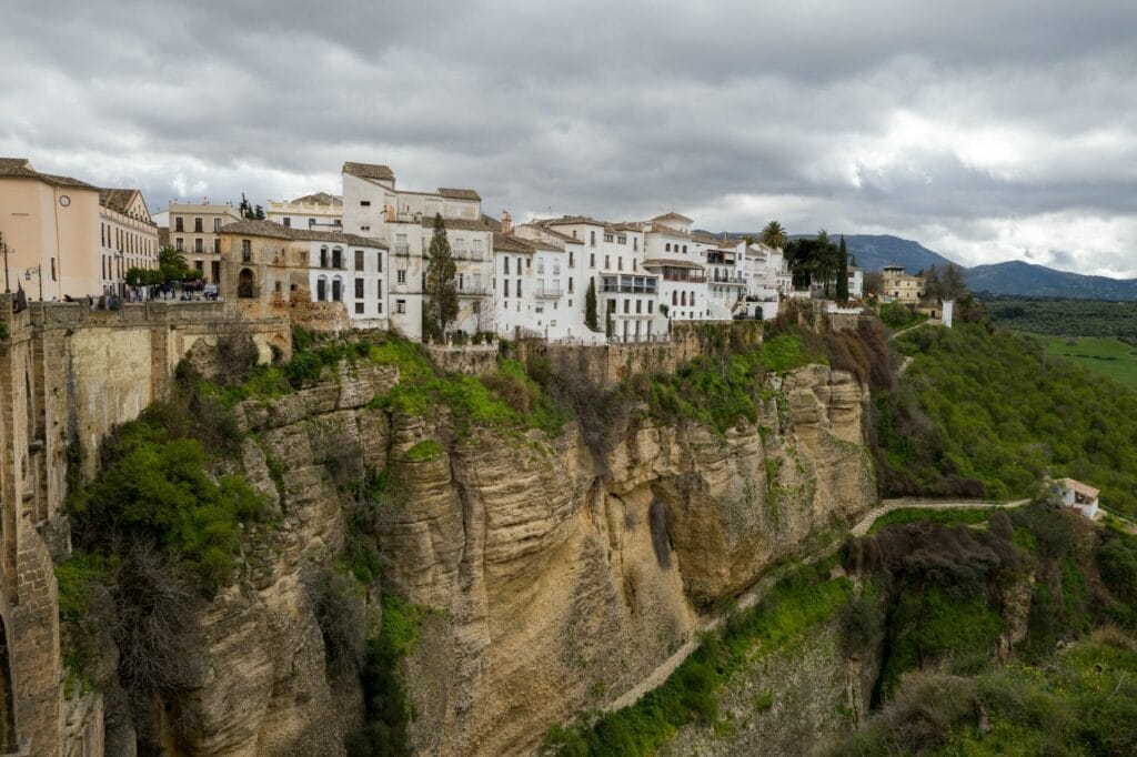 Cliffside white buildings in Ronda, Spain, with greenery.