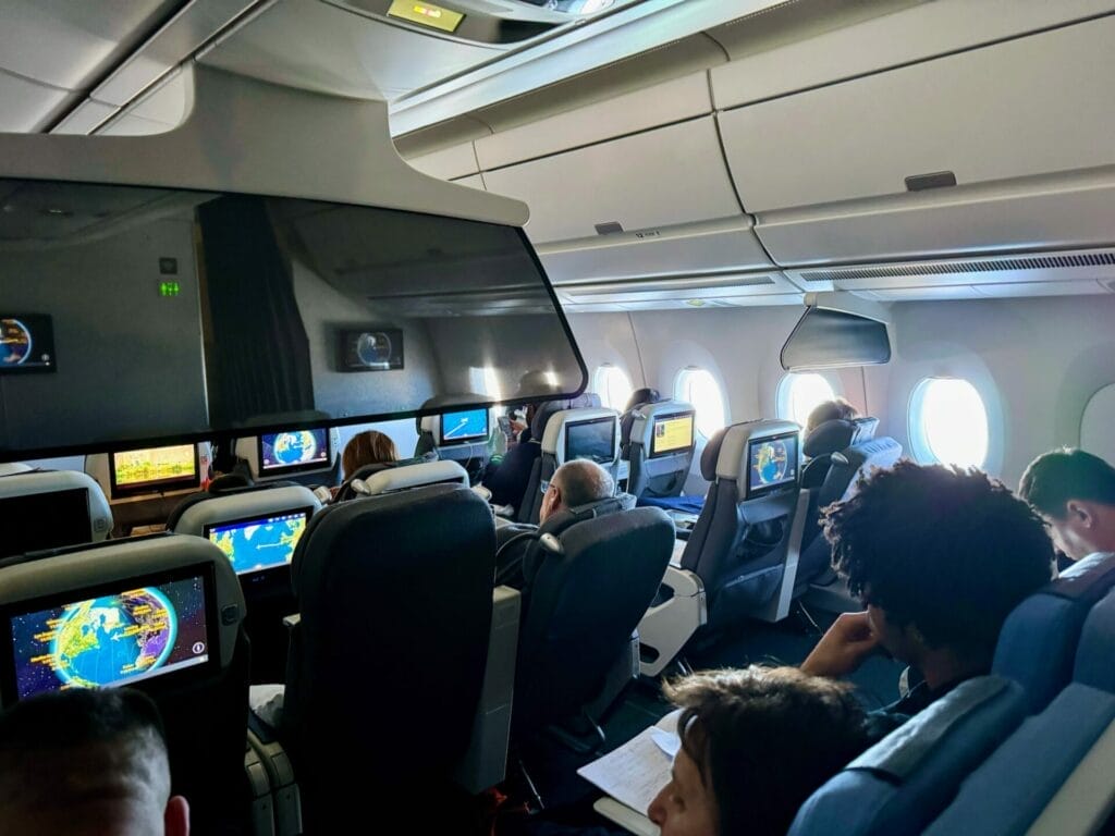 Passengers with screens on airplane cabin.