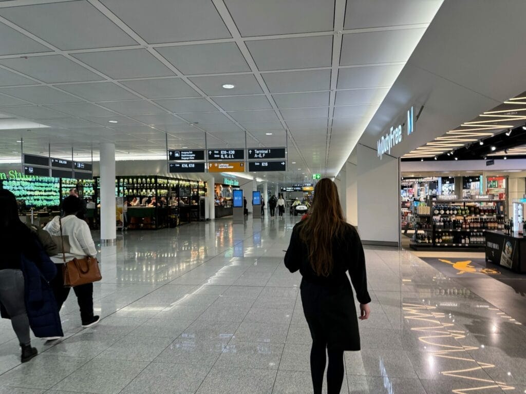 Passengers walking past duty-free shops in airport.