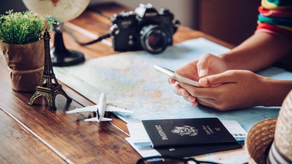 Person planning trip with map, phone, and passport