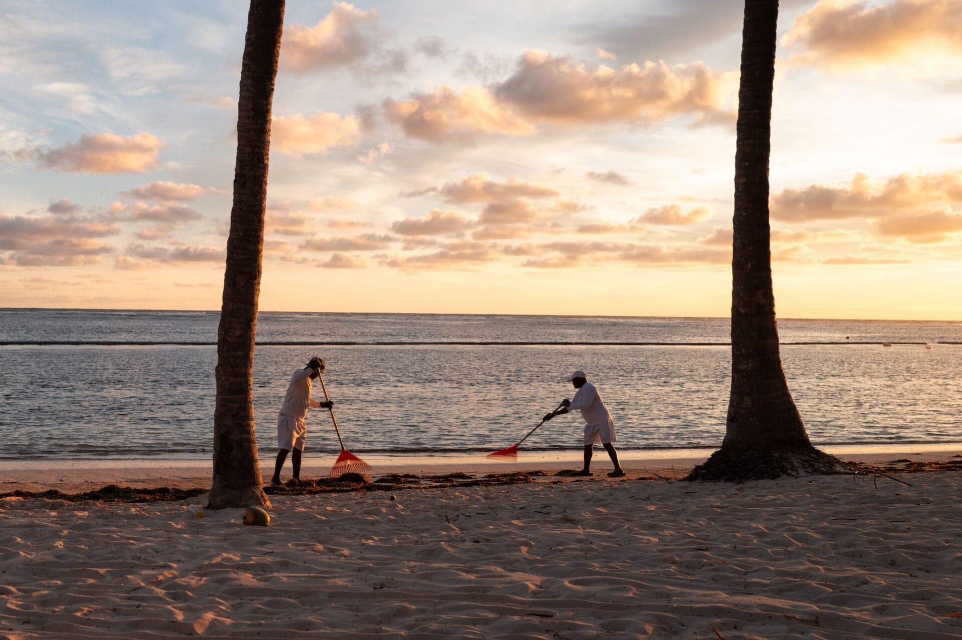 3 Resort Experience Every Traveler Should Know Two people raking beach at sunset