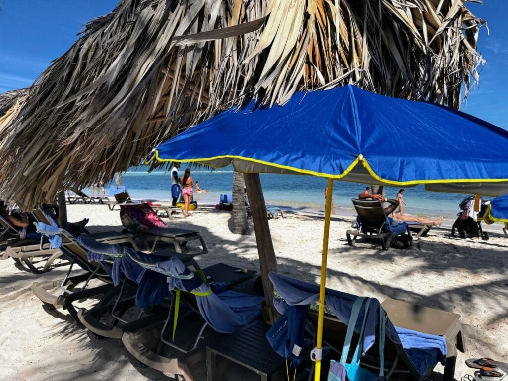 Sunny beach scene with blue umbrellas and relaxed visitors