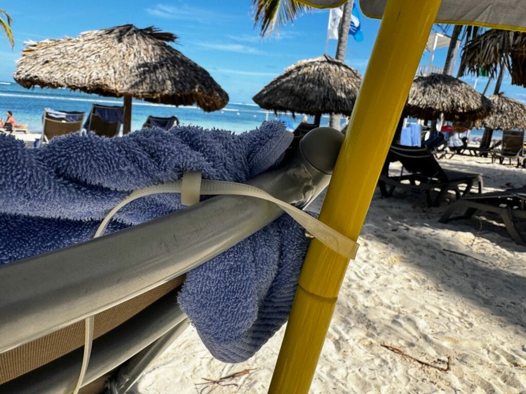 Towels hanging on chair, tropical beach with straw umbrellas