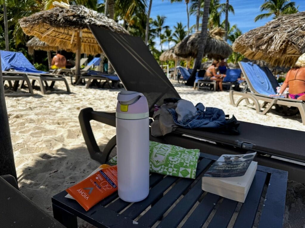 Beach scene with recliners, thermos, book, and sunscreen