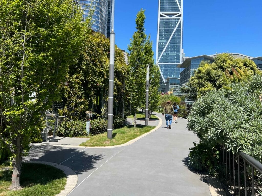 Urban park path with skyscrapers in background.