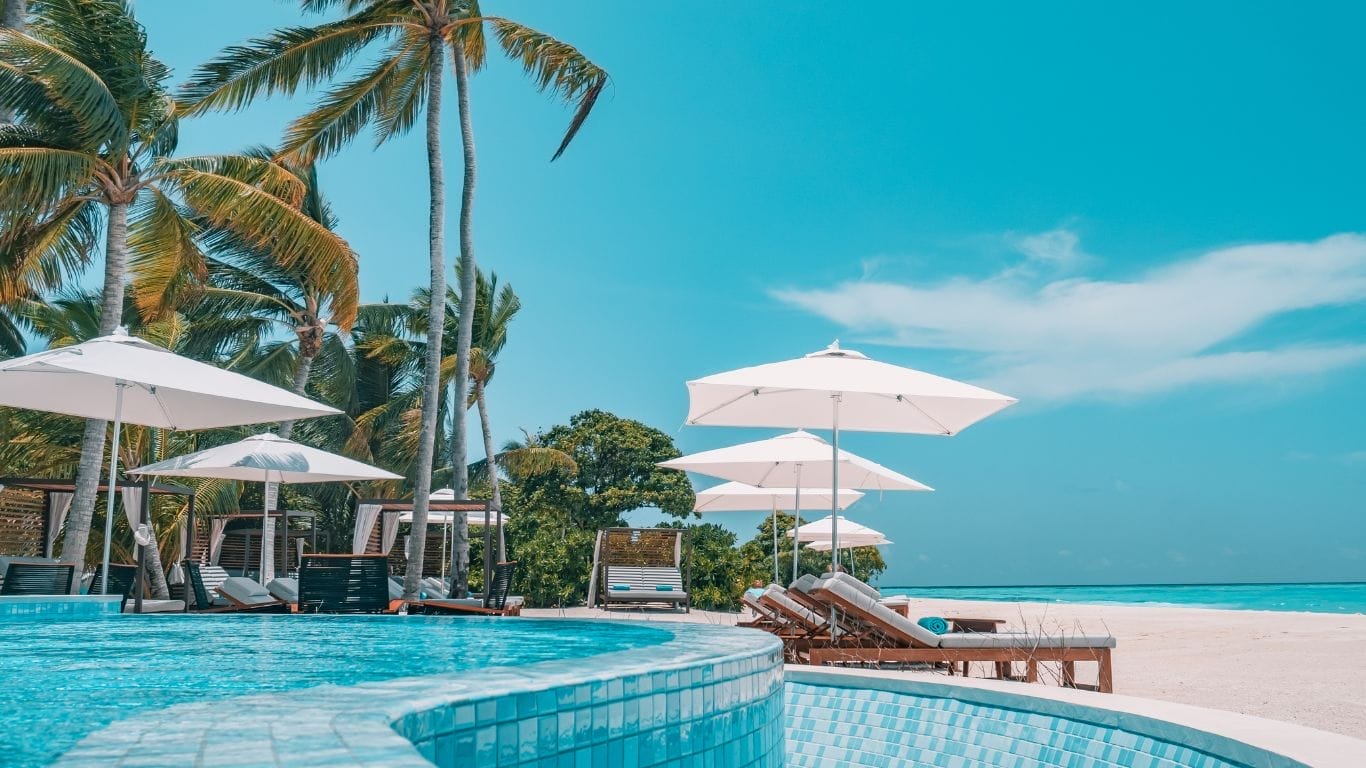Tropical beach with pool and umbrellas